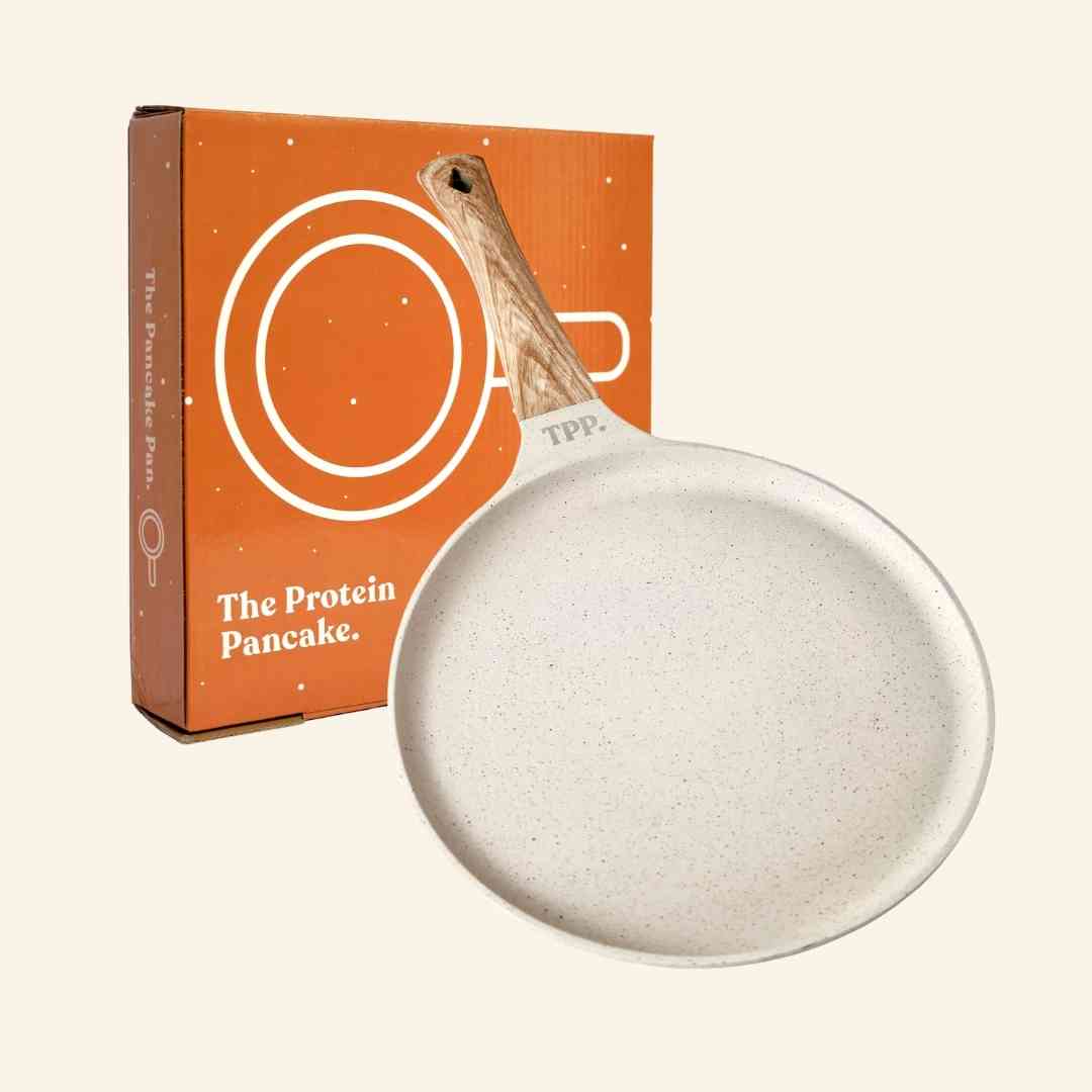 White frying pan with wooden handle beside an orange box labeled 'The Protein Pancake.'