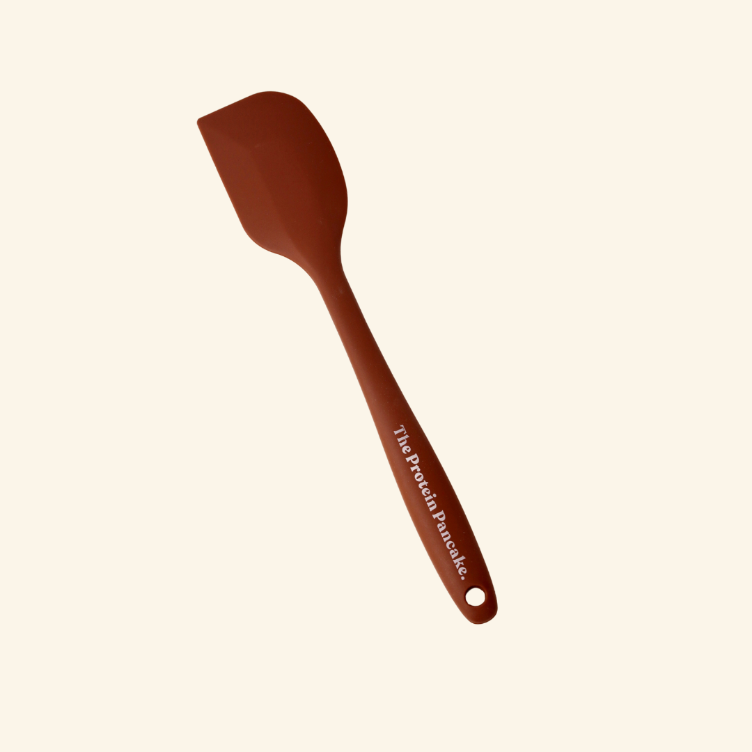 A brown silicone spatula on a beige background.