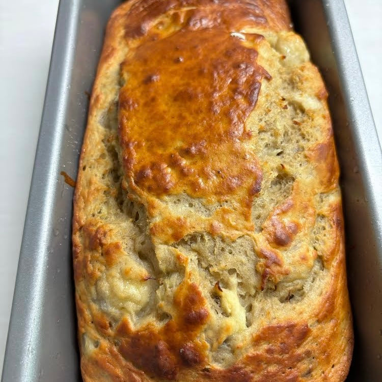 A freshly baked loaf of bread in a metal baking pan.