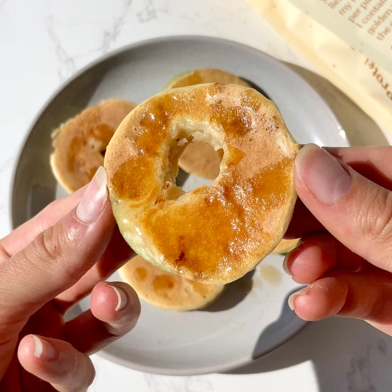 Person holding a apple protein ring over a plate in sunlight. 