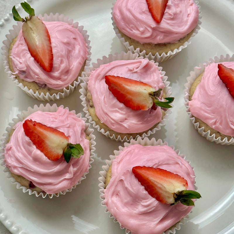 Pink frosted cupcakes with strawberry slices on a white plate. Protein Muffins.