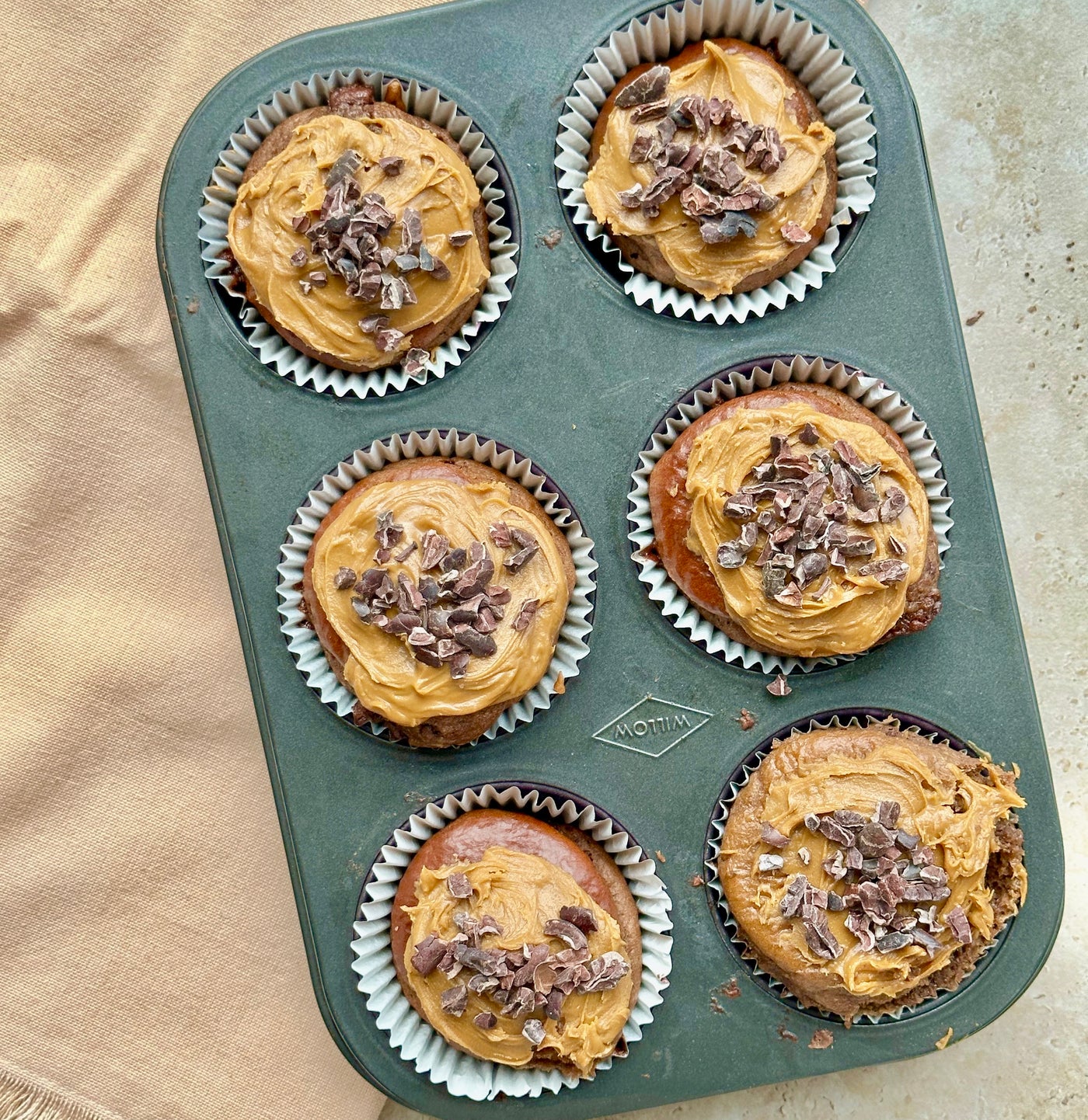 Muffins with peanut butter and chocolate shavings in a baking tray.