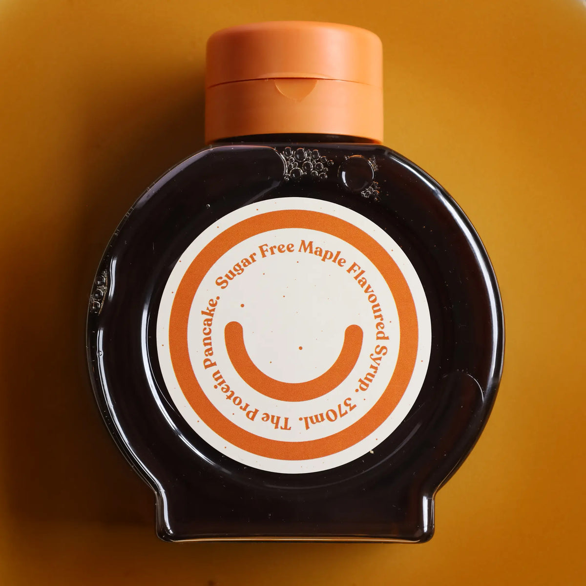 Bottle of sugar-free maple syrup with an orange cap on a yellow background